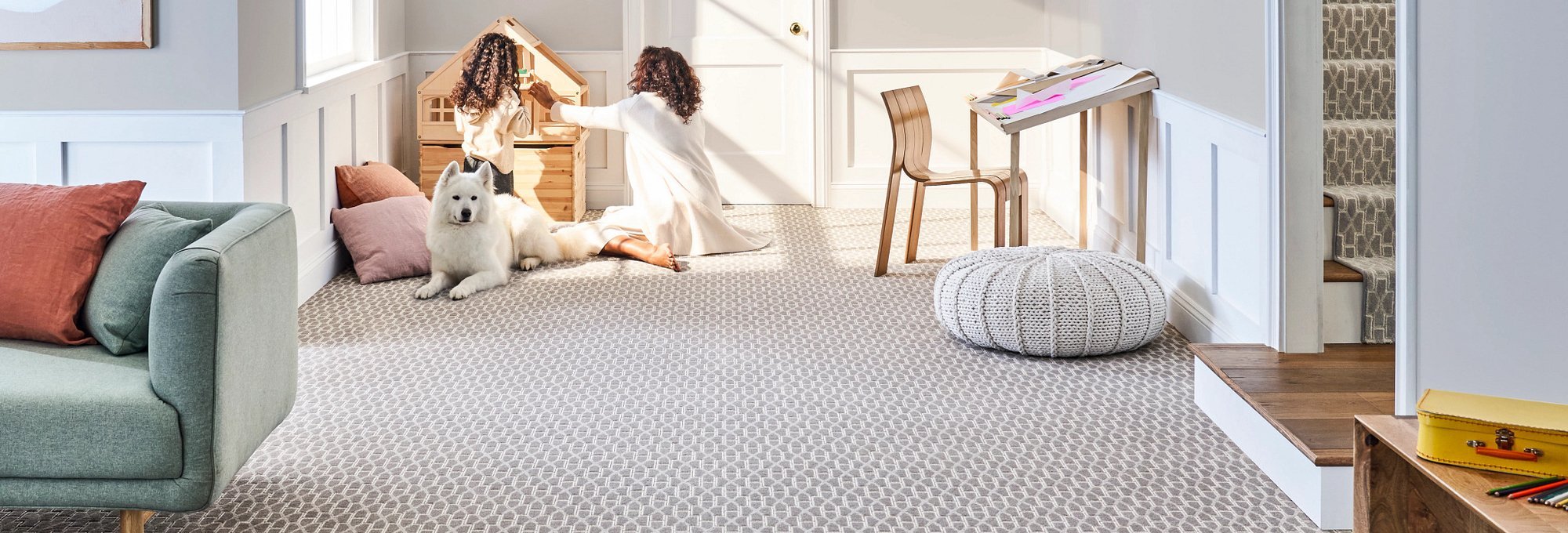 People and their dog playing in a living room with gray patterned carpet from Success Floor Covering LLC in Oakland, MD
